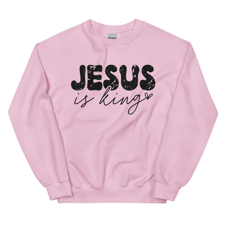 Light pink Christian sweatshirt with Jesus Is King text on the front, laid flat on a neutral background.